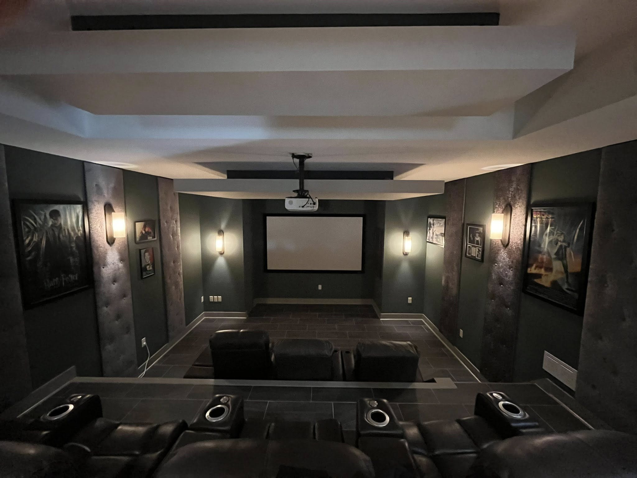 Dedicated home theater room featuring wall-mounted screen and surround sound speakers